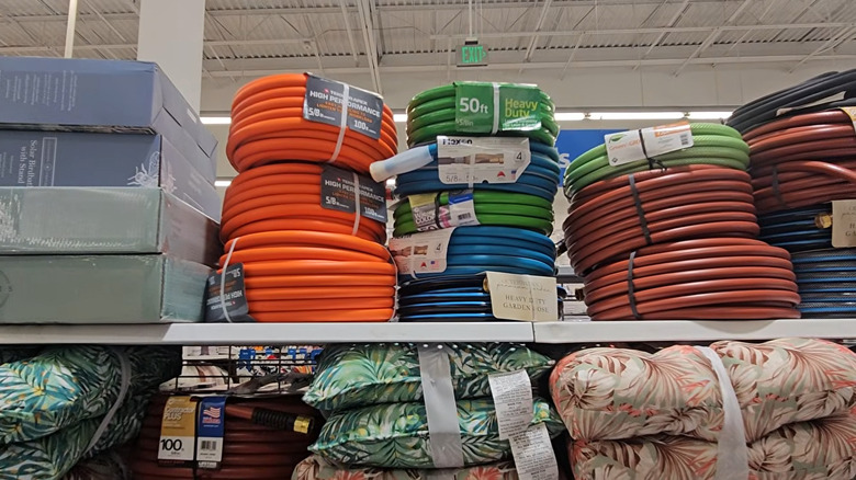 Garden hoses and outdoor pillows stacked on a store shelf
