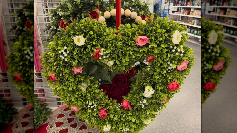 Faux green wreath with pink and yellow roses hung by a red ribbon in a Ross