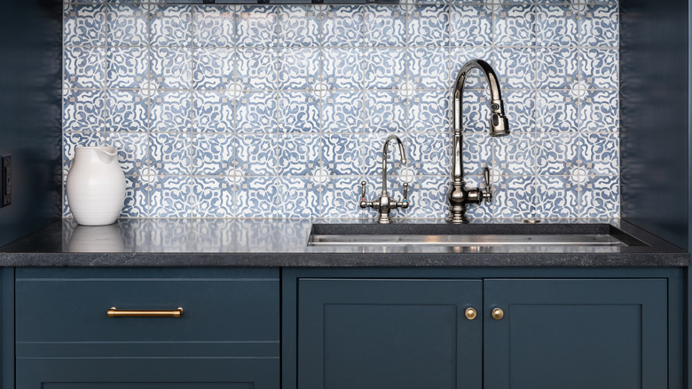 Bright modern kitchen with light wooden cabinets and dark backsplash and countertop, warm under-cabinet lights highlighting sink and stove for a cozy home interior.