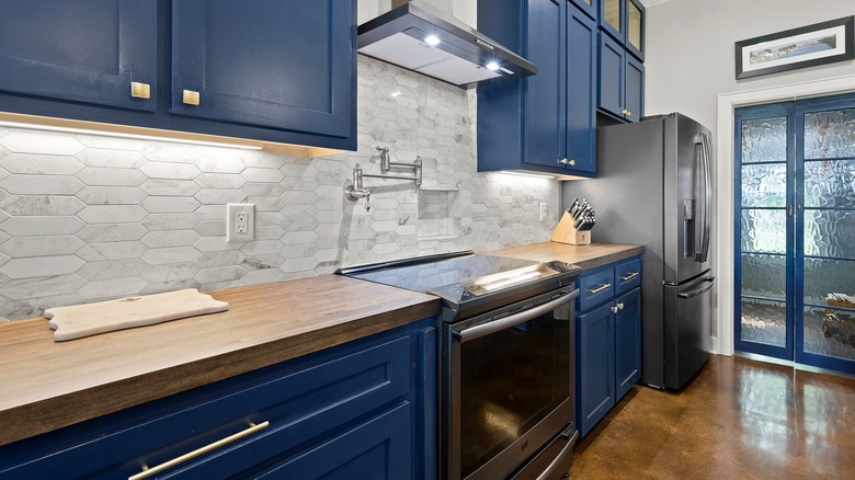Modified hexagon tiles as backsplash for dark blue kitchen cabinetry.