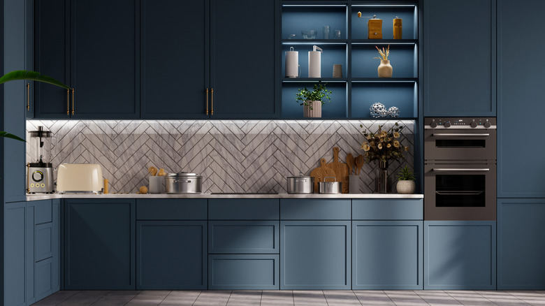 Herringbone tiles as backsplash of a dark kitchen.
