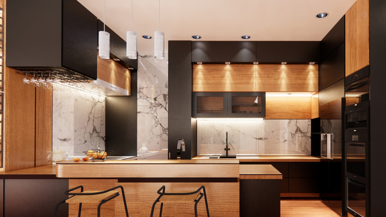 Mixed-material kitchen space, featuring wood, marble, and black-painted surfaces, and plenty of artificial lighting.