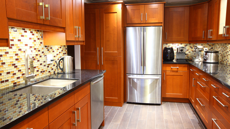 Colorful glass mosaic tiles as backsplash for kitchen featuring dark brown cabinets.