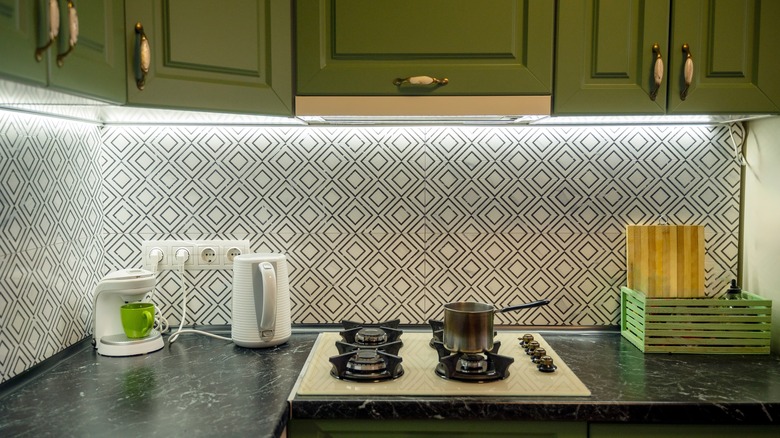 Quaint patterned tiles as backsplash with undercabinet lighting.