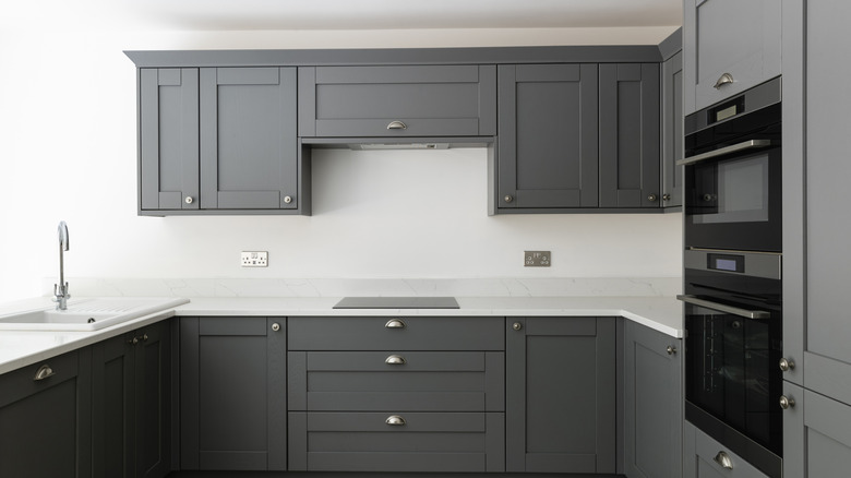 Dark cabinets with white countertop and plain white backsplash.
