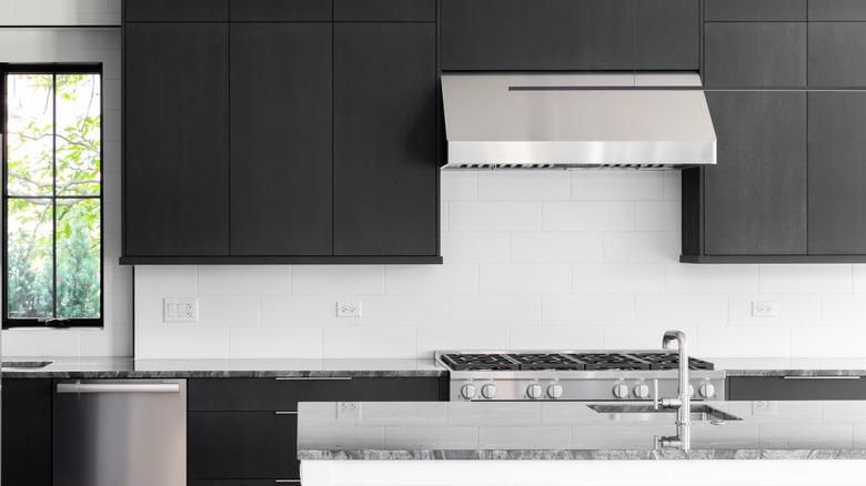 White subway tiles as backsplash of a kitchen with dark brown cabinetry.