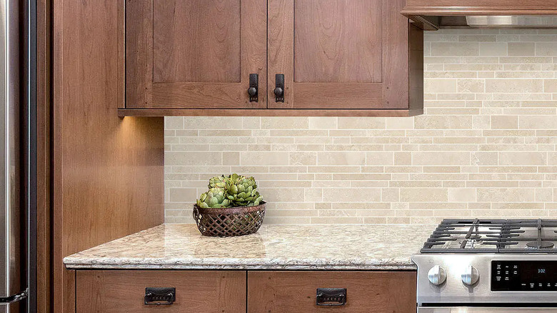 Light ivory travertine backsplash paired with dark wood kitchen cabinets.