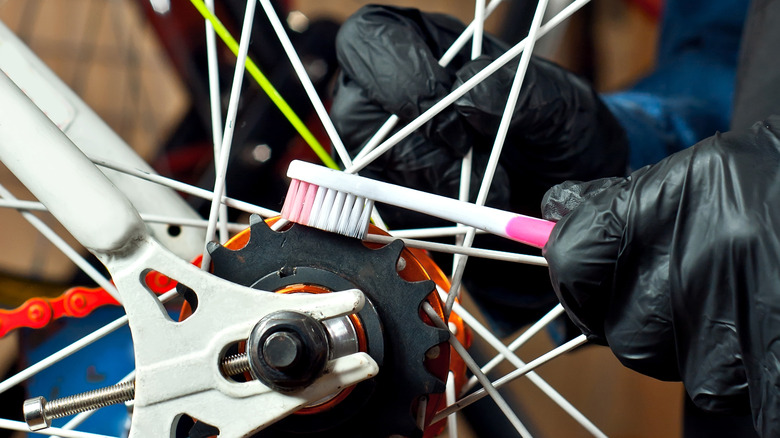 person cleaning bike chain with toothbrush