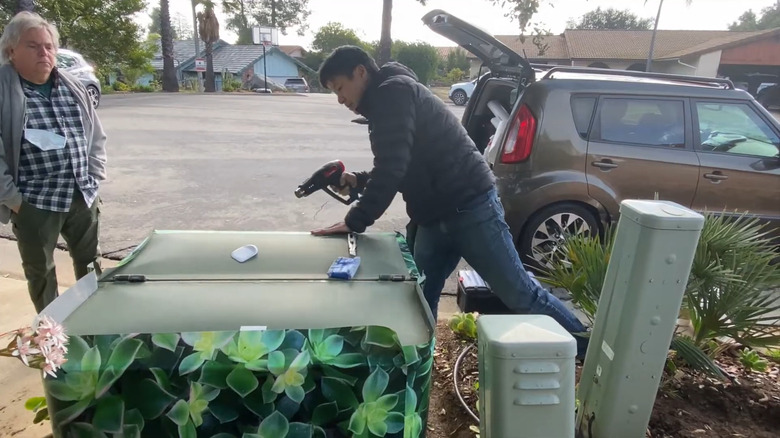 an artist installs uv resistant vinyl wrap to an electrical box
