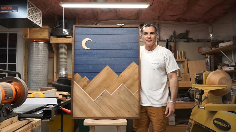 a wood worker shows off a wooden art panel, which could be used to cover up an outdoor electrical panel
