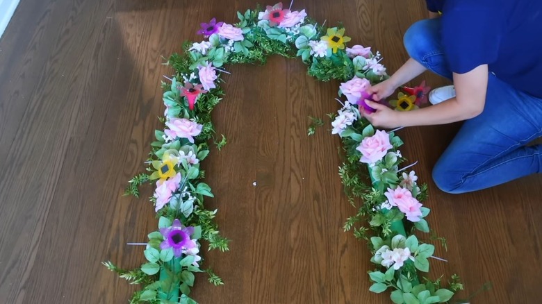 A woman making a faux floral arch featuring flower solar lights.