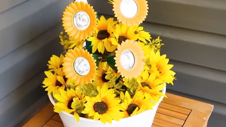 A white basket filled with faux sunflowers and sunflower solar lights.