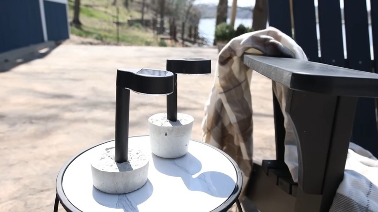Two solar lights rest in a Quikrete base to create portable outdoor lamps.