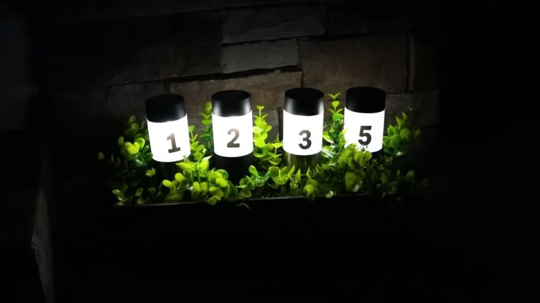 Four solar lights in a faux planter with the numbers "1235" on them.