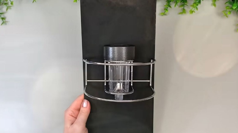 A napkin holder holds a solar light on a black sign.