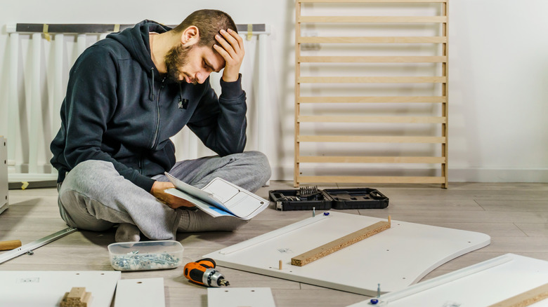 Man frustrated while assembling furniture