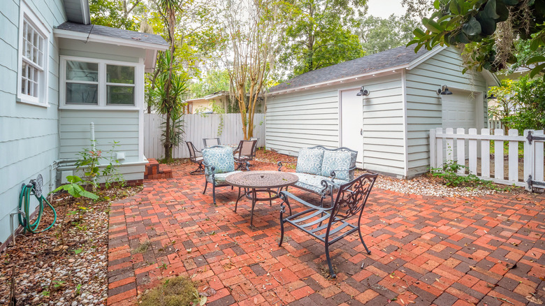A small patio with metal furniture and brick pavers