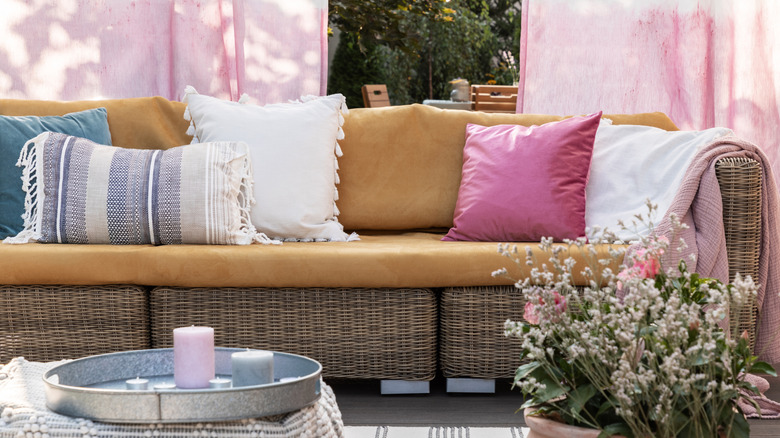 Wicker patio furniture with colorful pillows and throws