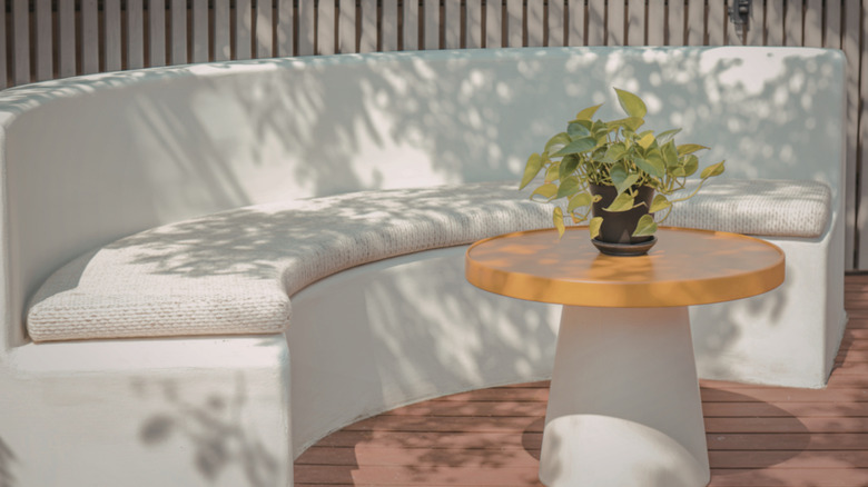 A white curved sofa and round center table on a patio