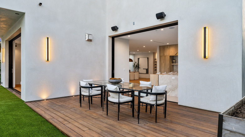 A wooden patio floor with dining table and chairs on it