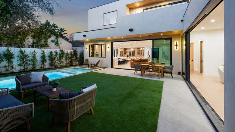 A modern patio with swimming pool, lounge area, and dining furniture