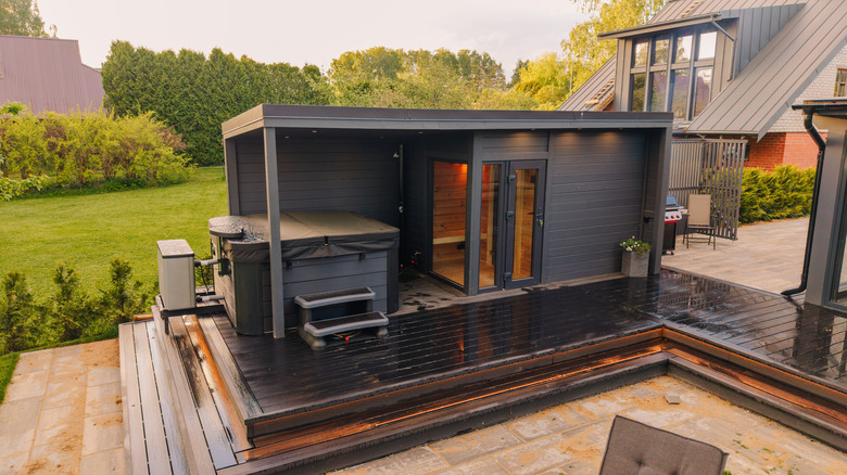 A covered sauna area with a hot tub on a patio