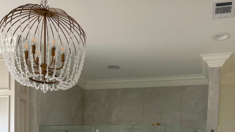 A large crystal chandelier in bathroom.