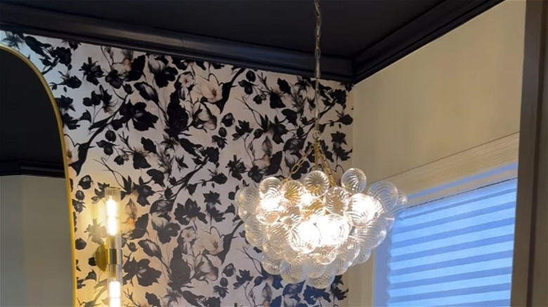 A black bathroom ceiling with chandelier and wallpapered wall