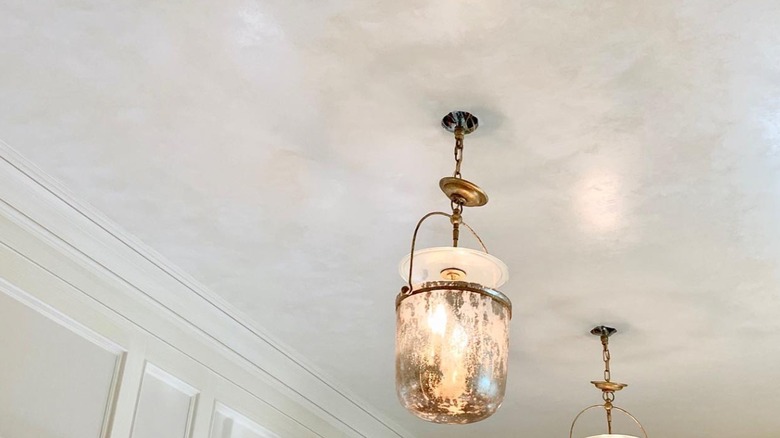 White ceiling glaze with hanging gold lighting fixture.