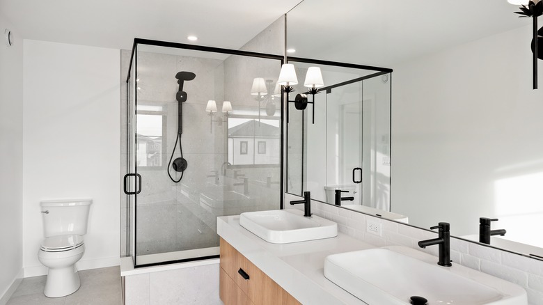 A white bathroom with black fixtures and a large shower.