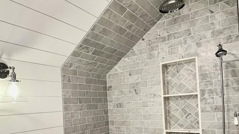 A slanted ceiling with tile and shiplap in bathroom.