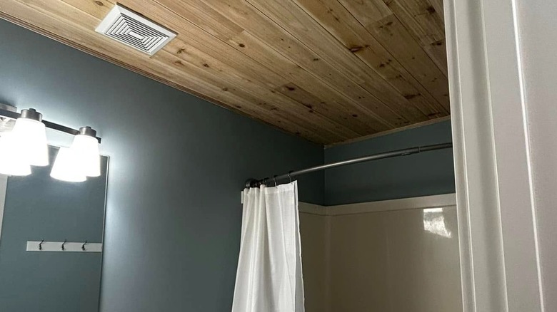 Wood shiplap ceiling with white vent in bathroom.