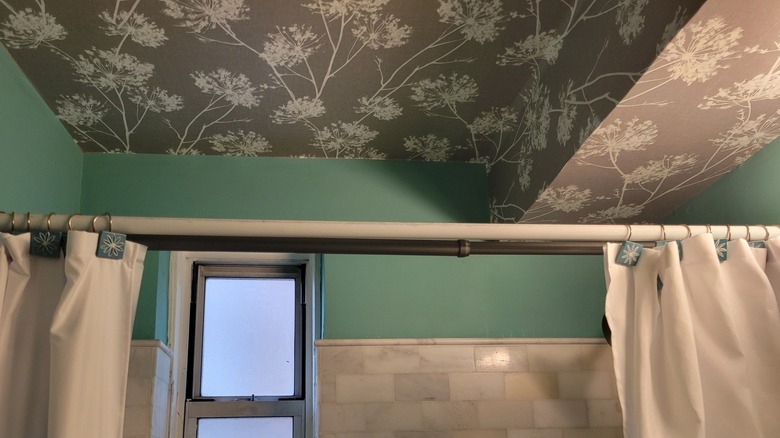 Black and white floral wallpaper ceiling above shower.
