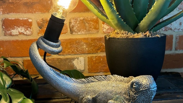 A silver iguana figurine with a lightbulb in its tail.