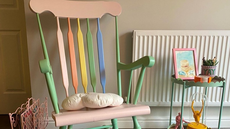 A multicolored chair with white pillow beside a green table