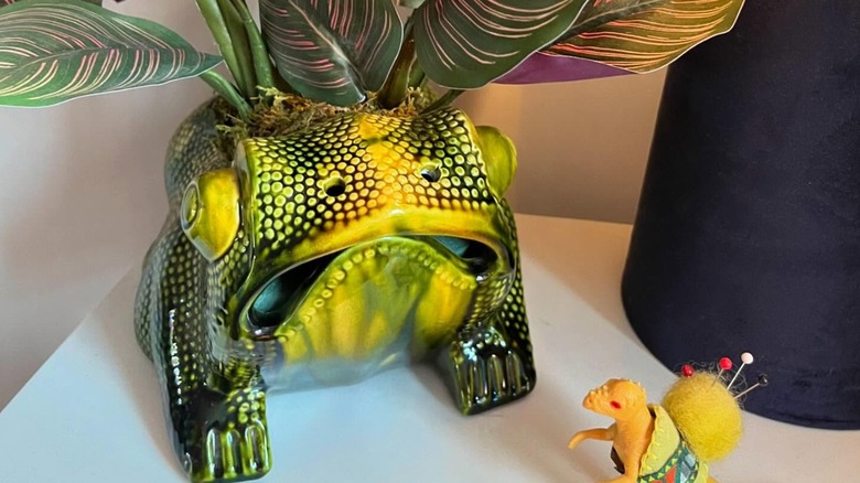 A yellow-green glazed toad planter on a white tabletop.