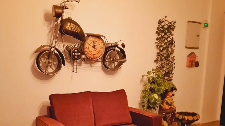 A motorcycle clock hanging on a beige wall.