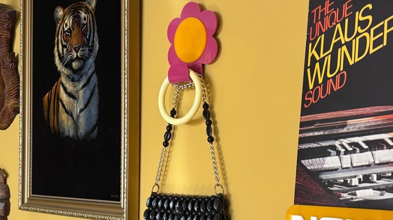 A pink and orange flower hook in a room with yellow walls.