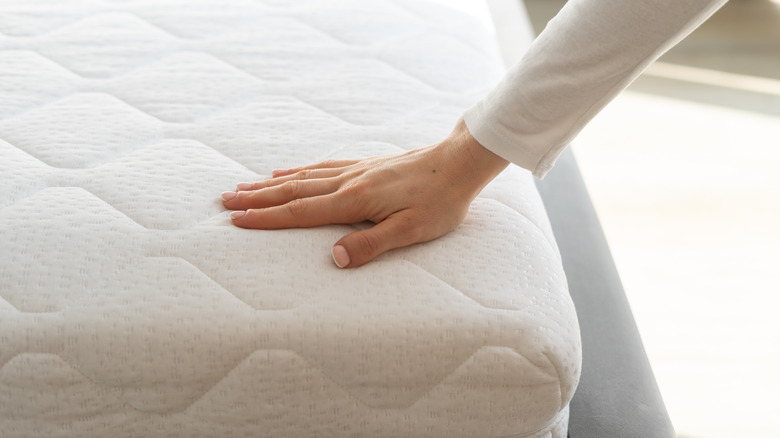 Close up of person touching bare mattress