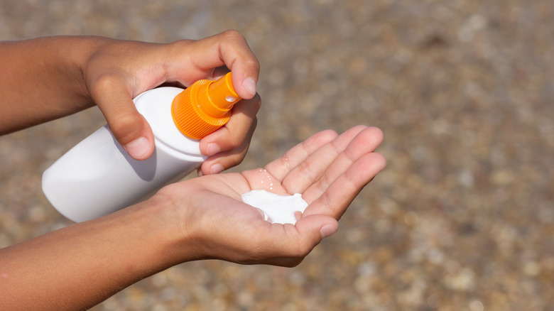 Close up of person applying sunscreen from a bottle