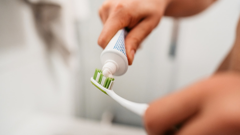 Close up of person squirting toothpaste onto their toothbrush