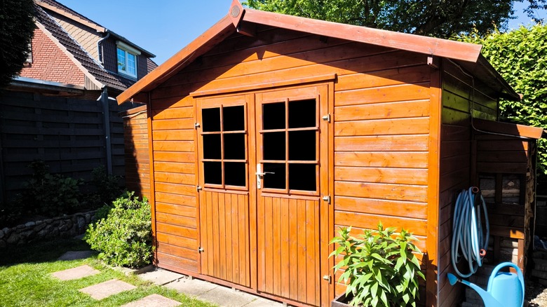 Small backyard shed in orange with double glass-paned doors