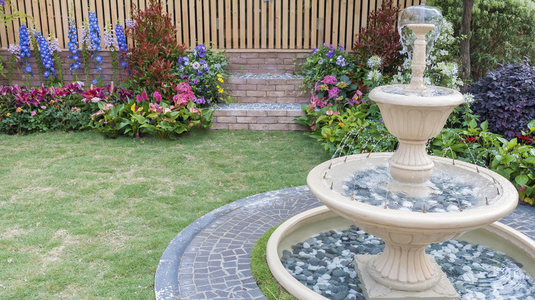 Fountain in a fenced yard, the fountain features grey and white stones across three levels