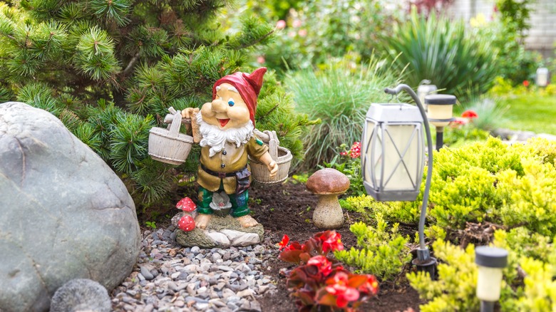 Lawn gnome depicted holding buckets in a yard filled with plants