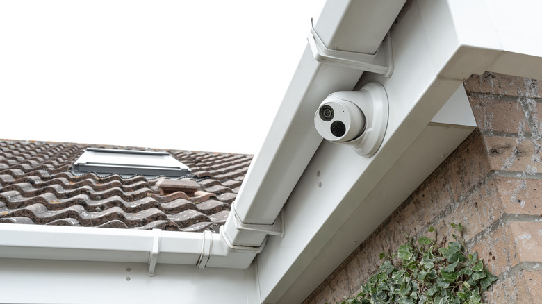 White security camera on side of house under the eaves