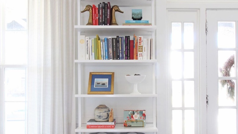 A white bookshelf holding books and decor near a front door