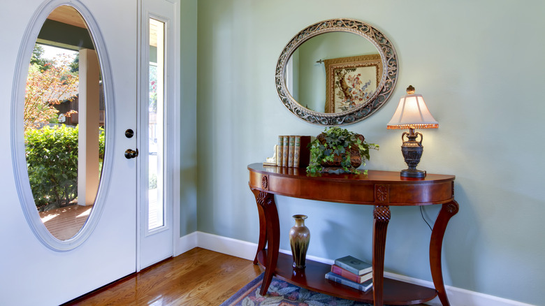 An antique mirror hanging above a dark-colored wood table