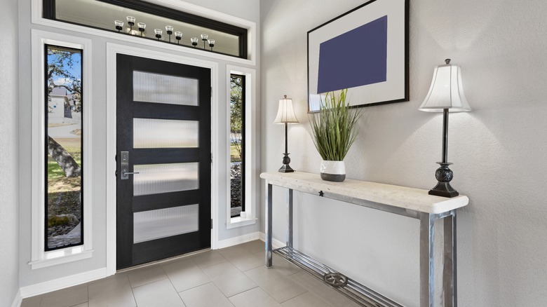 An entryway with a slim table holding two lit lamps