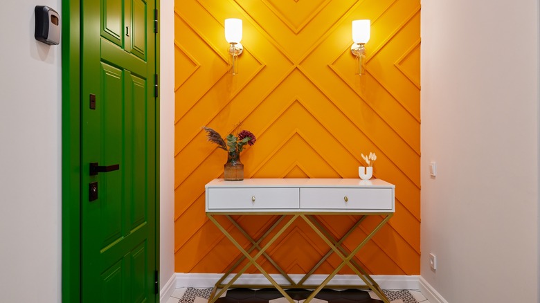 A green front door with orange accent wall in entryway