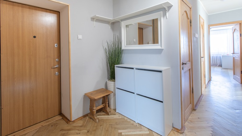 A simple entryway with pale blue shoe cabinet and a white mirror above